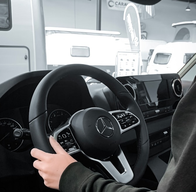 a person sitting in a car with a steering wheel