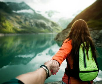 woman holding man's hand in front of water