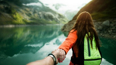 woman holding man's hand in front of water