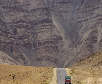 a truck driving down the road in front of a mountain