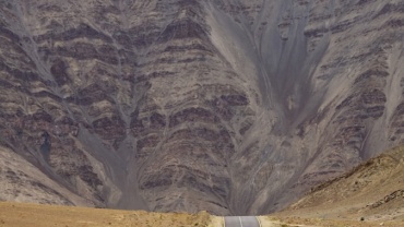a truck driving down the road in front of a mountain
