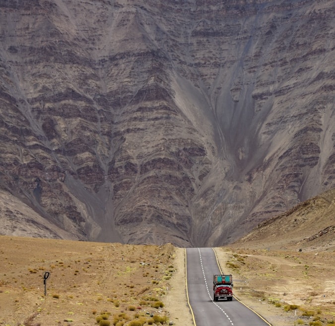 a truck driving down the road in front of a mountain