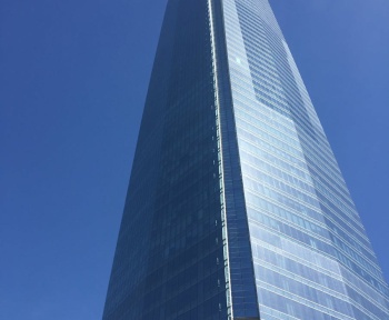 Low-angle view of Sky Costanera Tower, Santiago's iconic glass skyscraper, under a vivid blue sky.