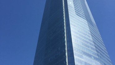 Low-angle view of Sky Costanera Tower, Santiago's iconic glass skyscraper, under a vivid blue sky.