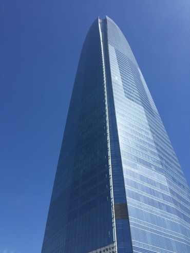 Low-angle view of Sky Costanera Tower, Santiago's iconic glass skyscraper, under a vivid blue sky.
