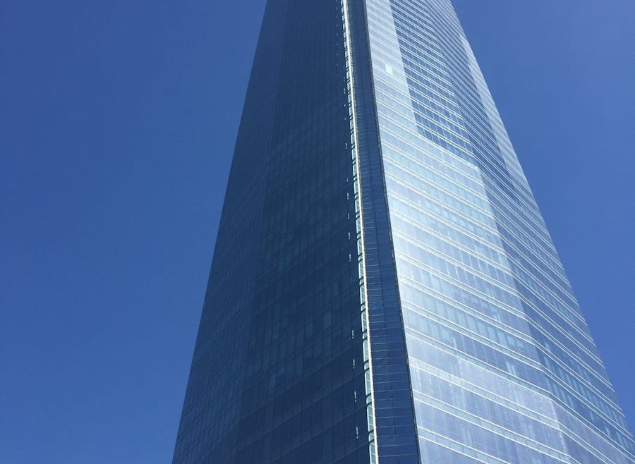 Low-angle view of Sky Costanera Tower, Santiago's iconic glass skyscraper, under a vivid blue sky.