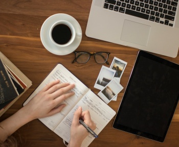 person holding ballpoint pen writing on notebook