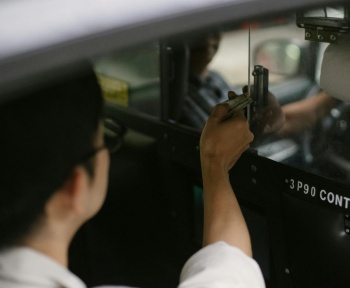 High angle of crop young male passenger in white shirt sitting in automobile and giving dollars to driver