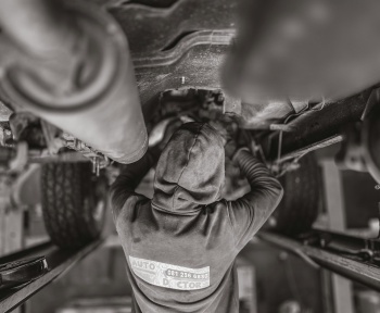 a black and white photo of a man working on a vehicle