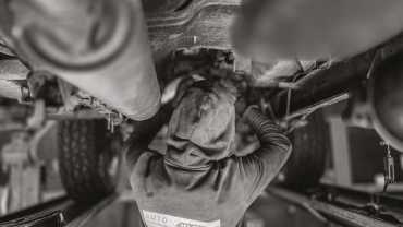 a black and white photo of a man working on a vehicle
