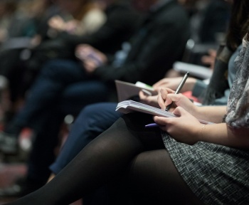 selective focus photography of people sitting on chairs while writing on notebooks