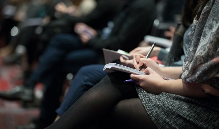 selective focus photography of people sitting on chairs while writing on notebooks