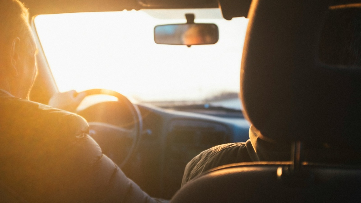 man driving car during golden hour