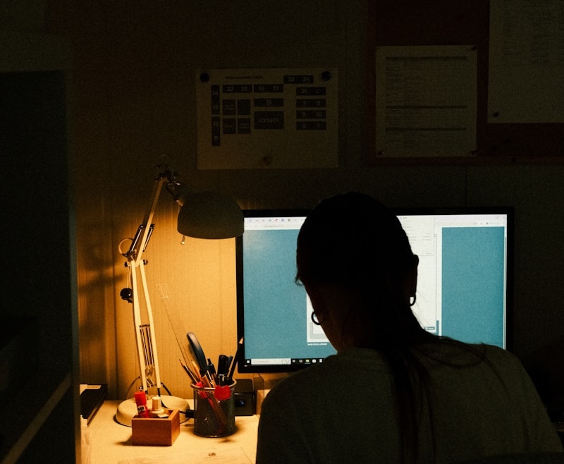 Person working on a computer in a dimly lit room.