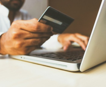 person using laptop computer holding card