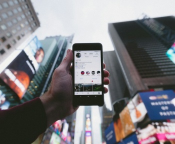 high angle photo of person holding turned on smartphone with tall buildings background